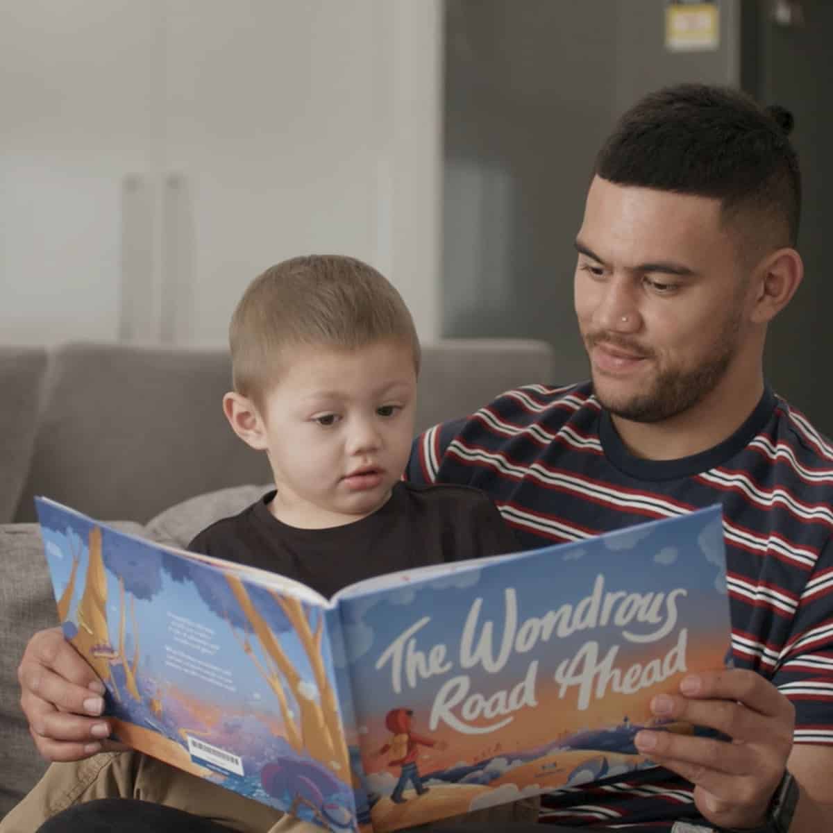 Father reading a book to his kid from the Redkite Book Club service which provides free resources for cancer patients